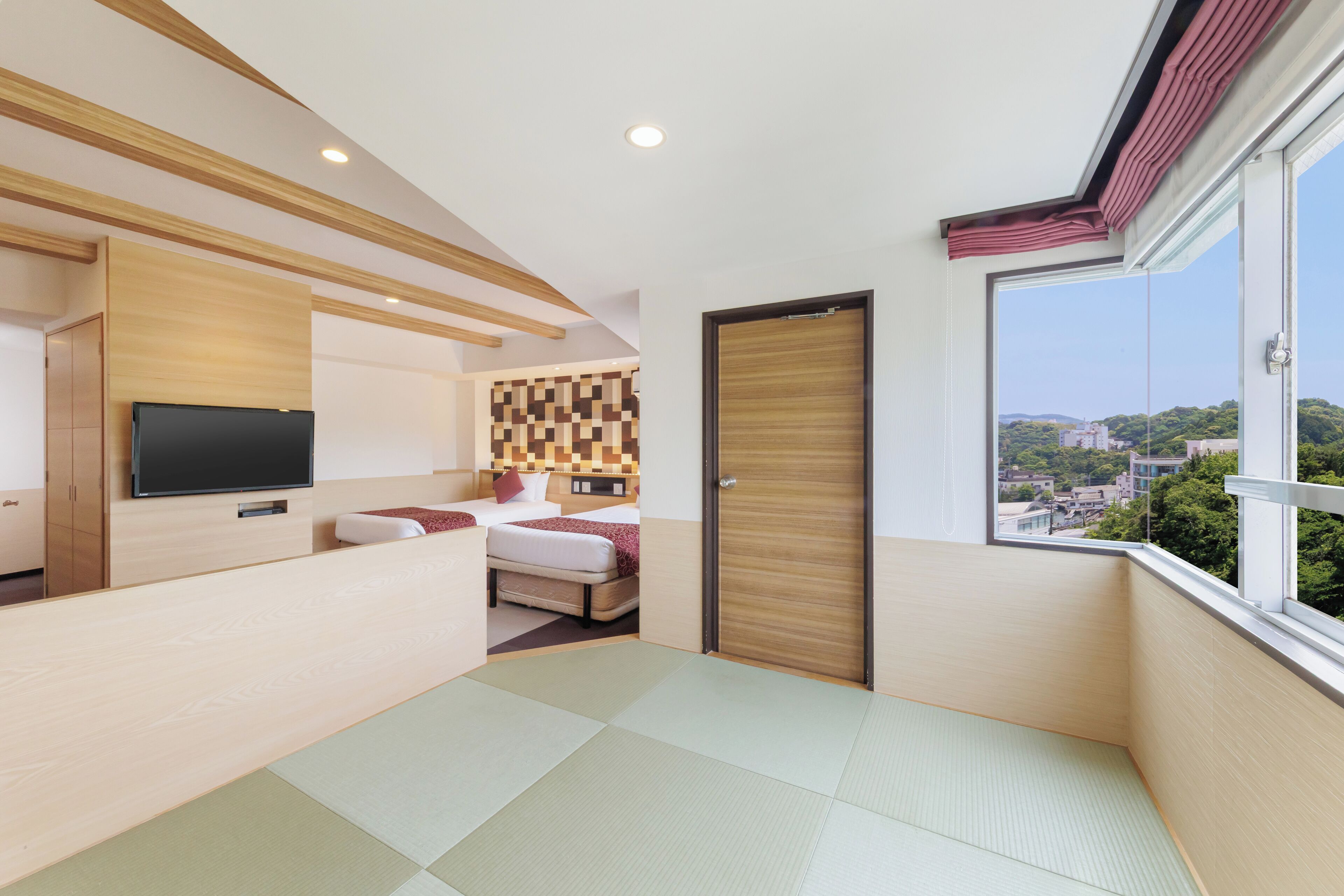 Camera d'hotel moderna con un letto, una TV, una testiera in legno, vista sulla città e una porta scorrevole.