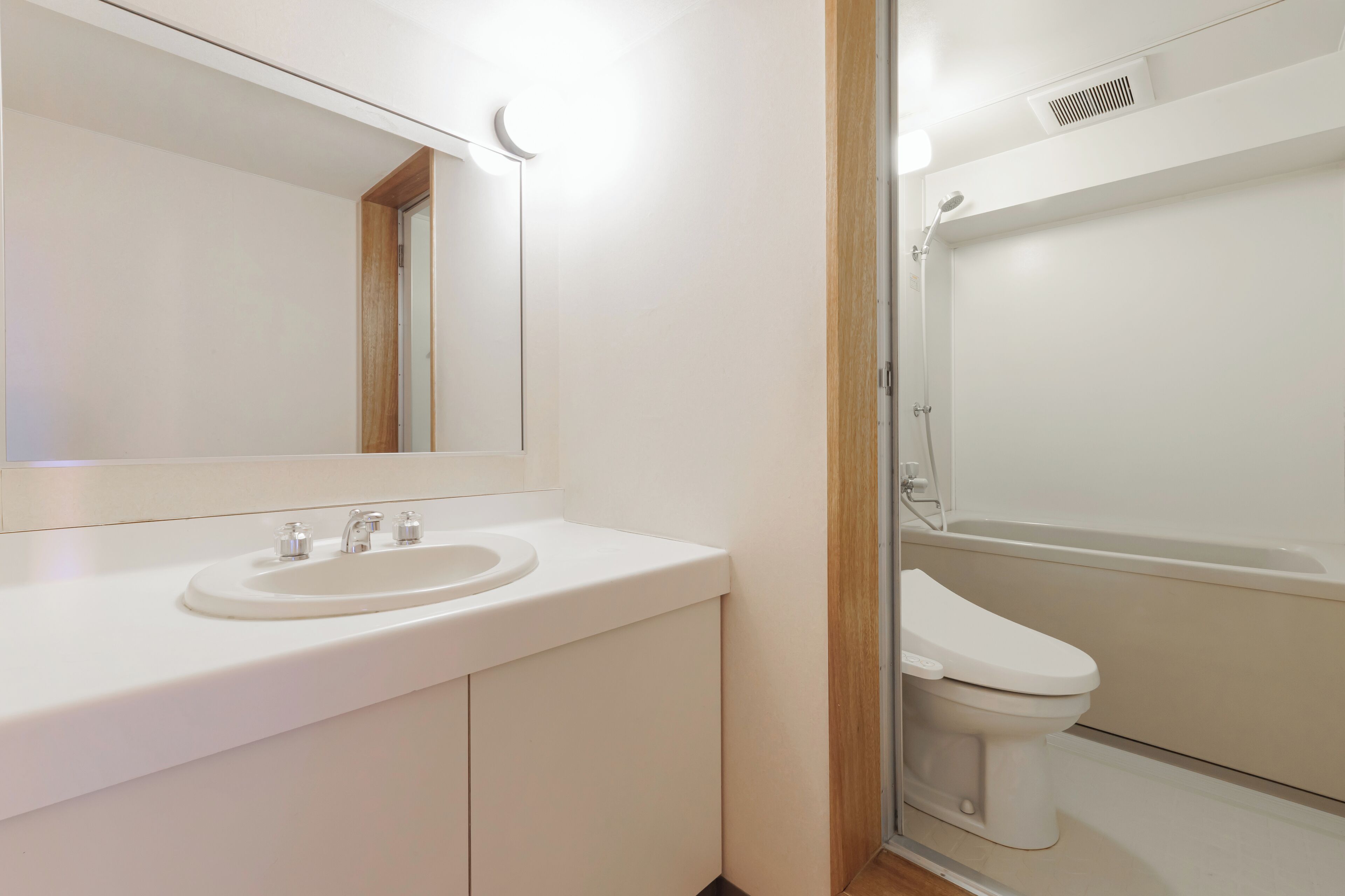 Une salle de bain avec un lavabo blanc, un miroir et des toilettes.