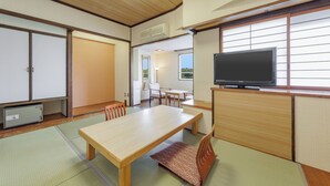 A traditional Japanese room with tatami flooring, a low wooden table, a television, and sliding doors. - Wan Wan Paradise Toba (Toba)