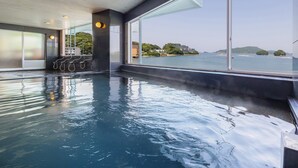 An indoor swimming pool with clear views of the sea and distant islands. - Wan Wan Paradise Toba (Toba)