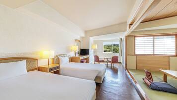 A hotel room with two beds, a TV, a desk, and a view of the outdoors.