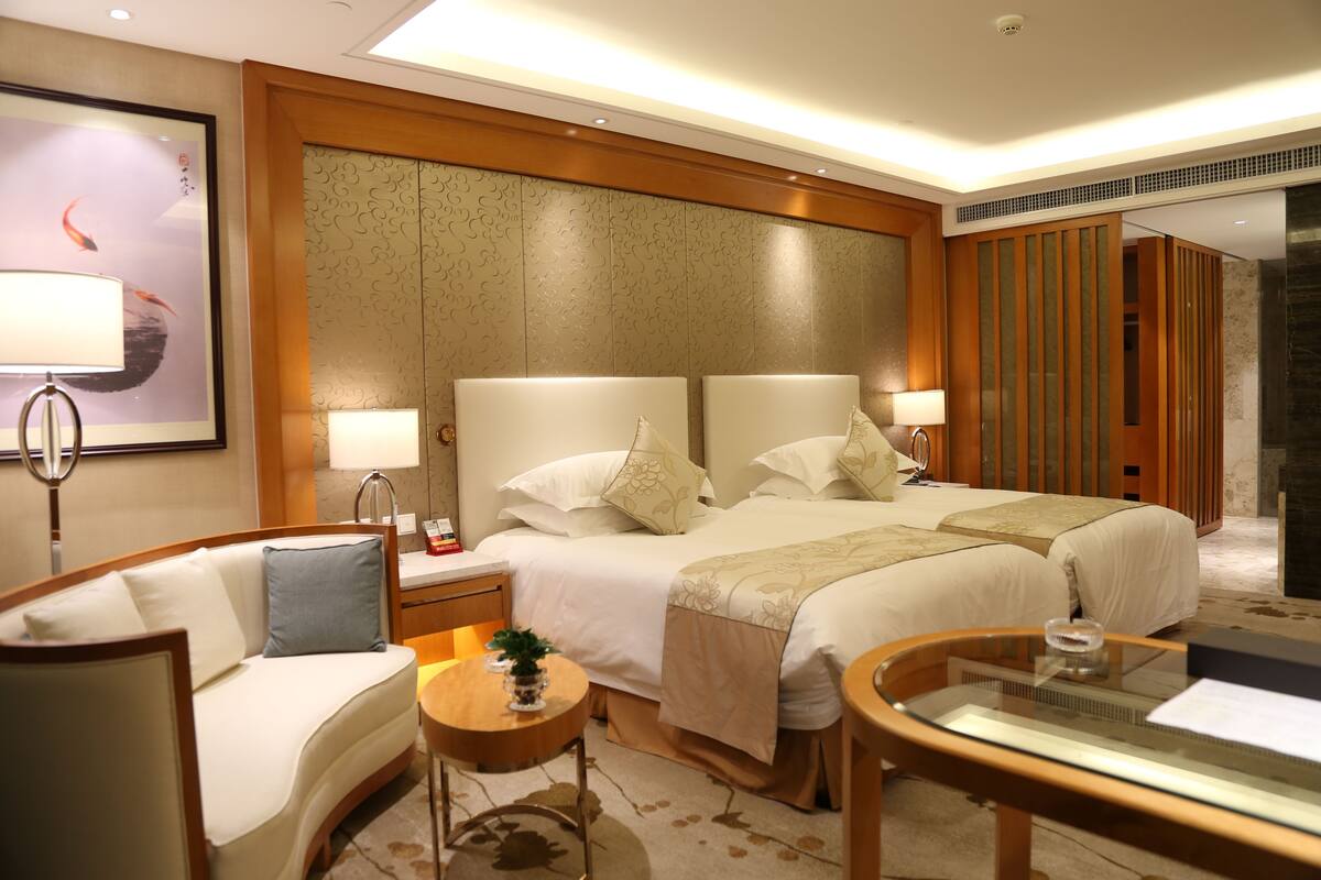 Ein Hotelzimmer mit zwei Betten, einem Sofa, einem kleinen Tisch und einem Spiegel.