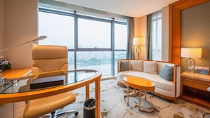 Une chambre d’hôtel moderne dotée d’une grande fenêtre, d’un bureau avec une chaise, d’un canapé et d’une petite table.