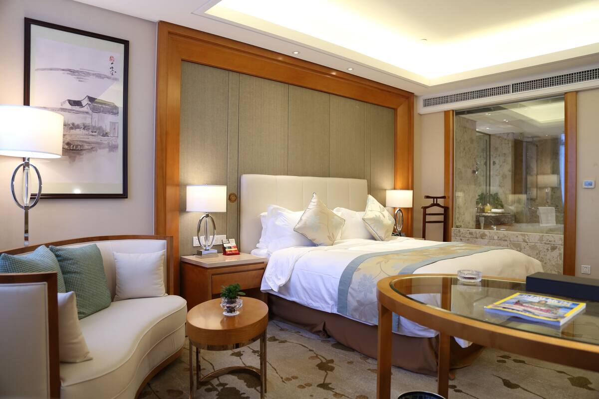 Ein Hotelzimmer mit einem Bett, einer Couch, einem kleinen Tisch und einem Glastisch.