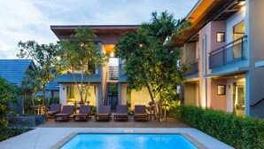 A modern hotel with a swimming pool, outdoor seating, and lush greenery. - Parida Resort (Choeng Thale)