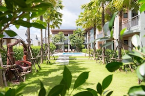 A resort with a pool, palm trees, and a clear sky. - Parida Resort (Choeng Thale)
