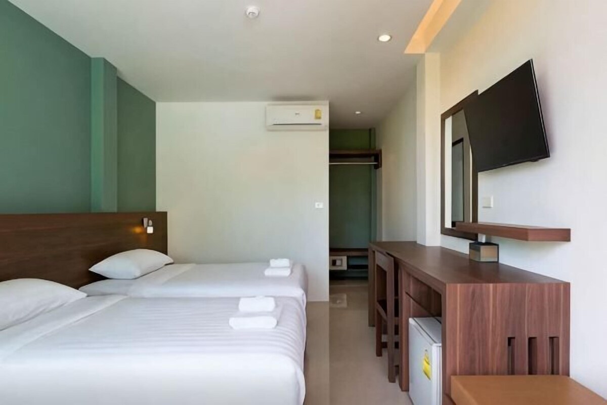 A hotel room with two beds, a desk, a TV, and a wardrobe.