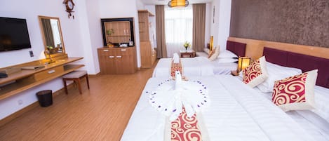 A hotel room with a large bed, a desk with a chair, a television, and a wardrobe.
