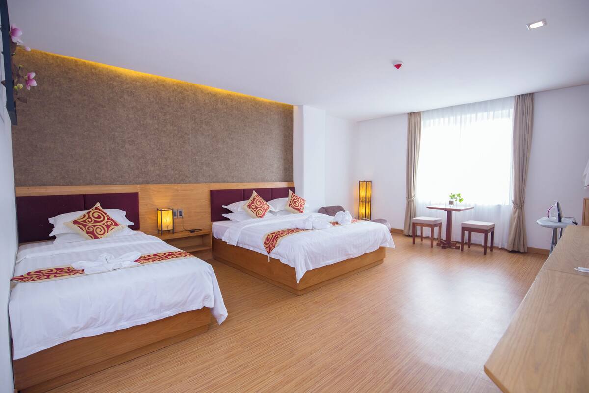 Ein Hotelzimmer mit zwei Betten, einem kleinen Tisch und einem Schreibtisch.