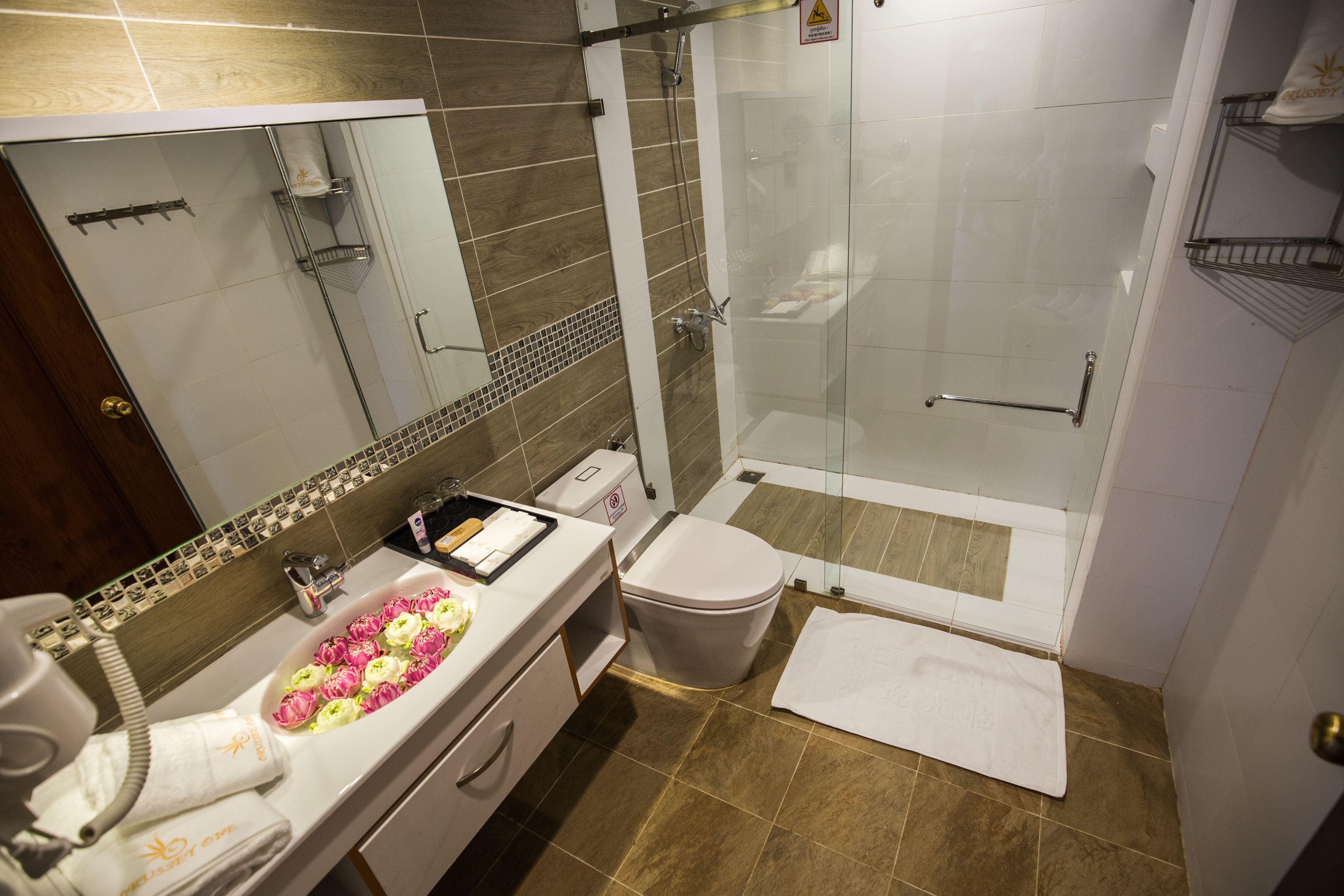 A bathroom with a glass shower enclosure, a white sink with a towel rack, and a toilet.