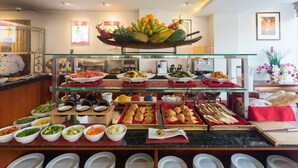A buffet with various food items including fruits, vegetables, and pastries.