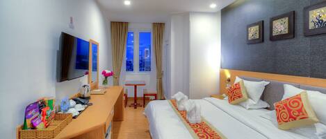 A hotel room with a bed, a desk, a TV, and a window with curtains.