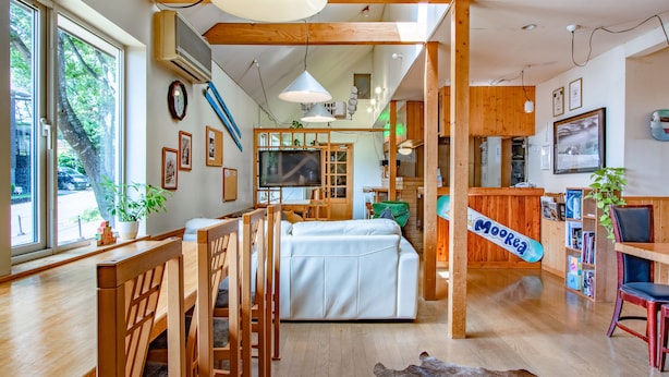 Un interior moderno con muebles de madera, un sofá, una zona de comedor y una barra.
