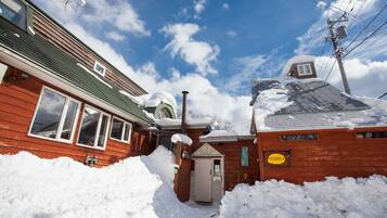 A wooden building with a snow-covered roof and a small attached structure.