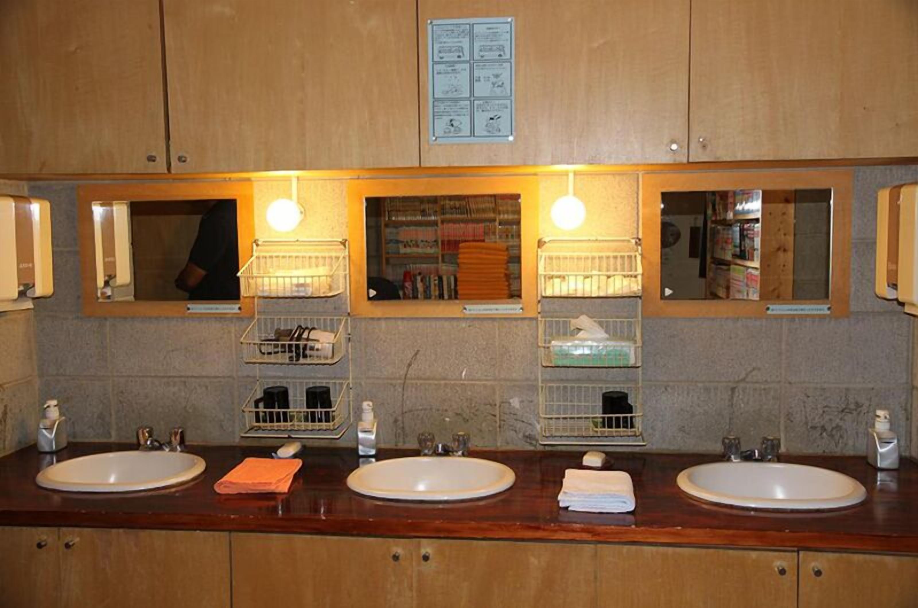 A public restroom with two sinks, mirrors, and shelves with toiletries.