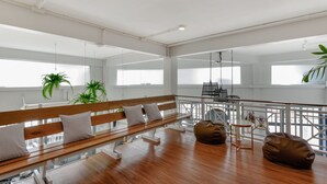 Amplia habitación con un banco de madera, dos pufs y una barandilla con vistas a un balcón.