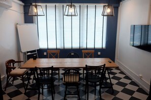 Une salle de conférence avec un sol à carreaux, une longue table en bois et quatre chaises.
