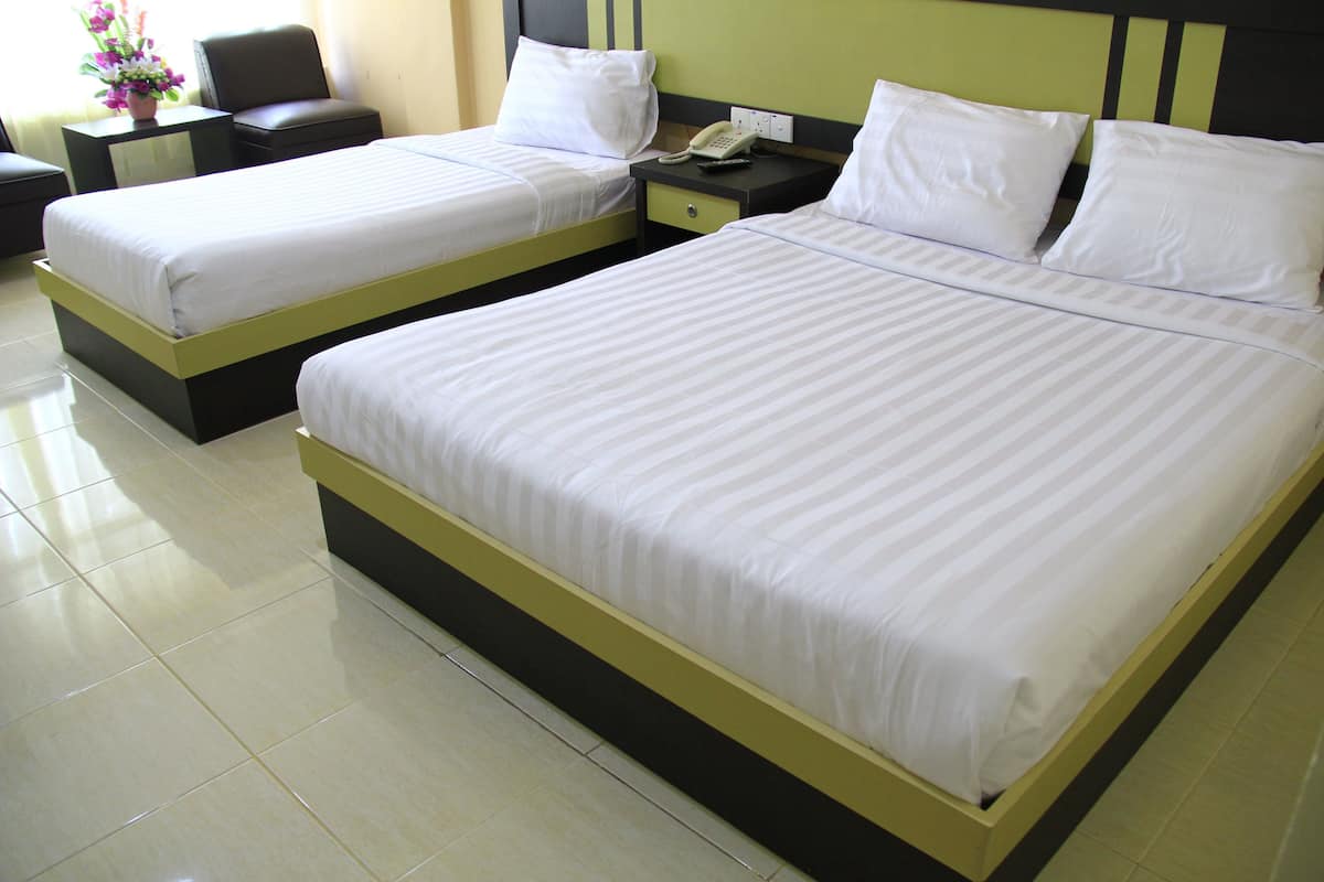 A hotel room with two single beds, a nightstand with a phone, and a small table with a vase of flowers.