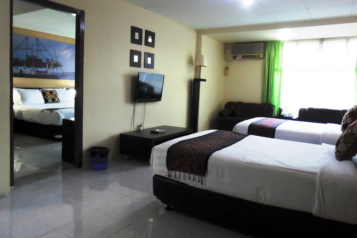 A hotel room with two beds, a TV, a desk, a mirror, and a window with curtains.