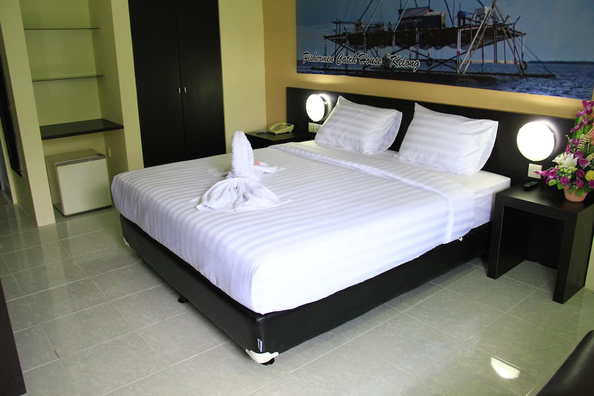 A neatly made bed with white linens and pillows, a bedside table with a lamp, and a wall-mounted shelf.