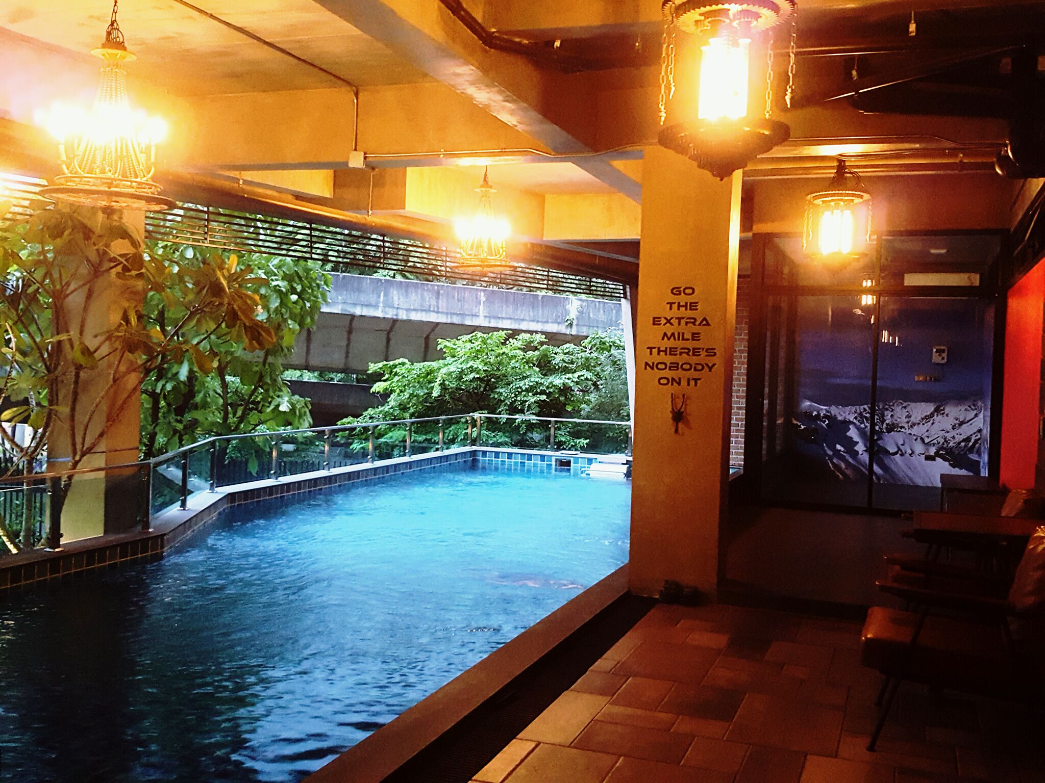 An indoor swimming pool with a view of greenery and a mural.
