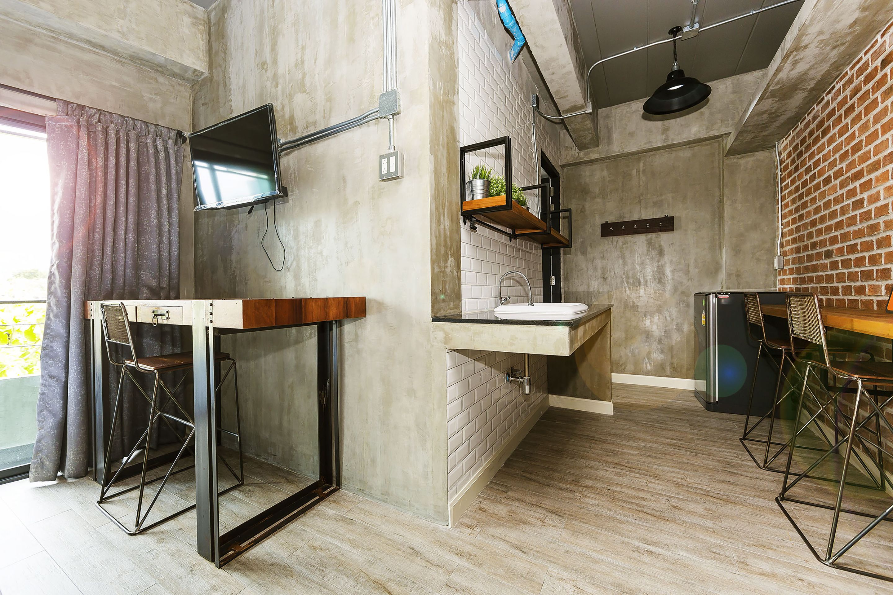 A modern kitchen with a built-in sink, a dining area with stools, and a large window with curtains.
