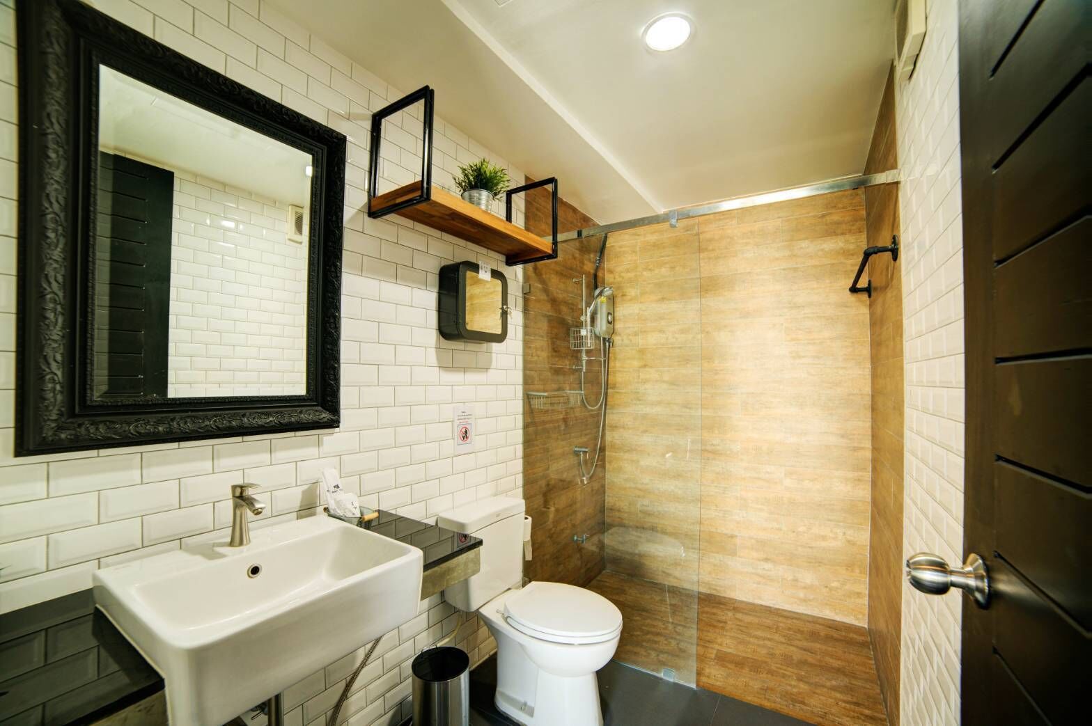 A bathroom with a white sink, a toilet, a shower with a glass door, and a mirror with a black frame.