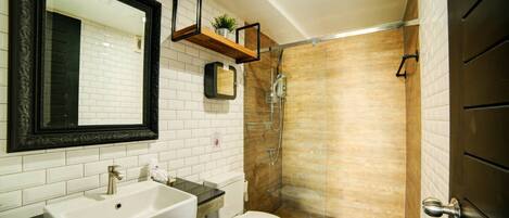 A bathroom with a white sink, a toilet, a shower with a glass door, and a mirror with a black frame.