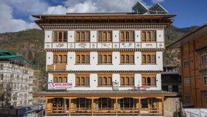 Een meerlaags gebouw met een bord voor Hotel Bhutan, met traditionele houten balkonnetjes en een geruite gevel.