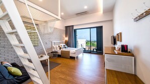 Ein modernes Schlafzimmer mit Schlafgalerie, einem Balkon mit Blick und einer kleinen Sitzecke mit Sofa und Couchtisch.