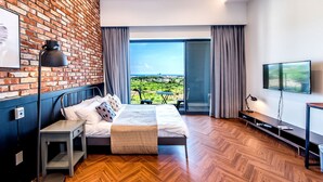 Ein modernes Hotelzimmer mit Backsteinwand, großem Fenster mit Blick, einem Bett, einem Schreibtisch und einem Fernseher.