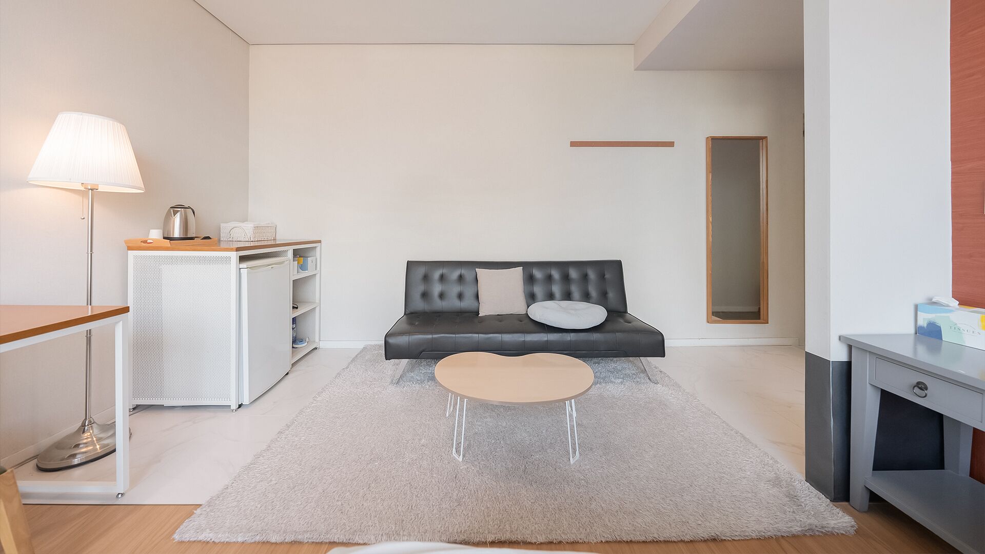 A modern living room with a sofa, a small coffee table, a lamp, and a cabinet.