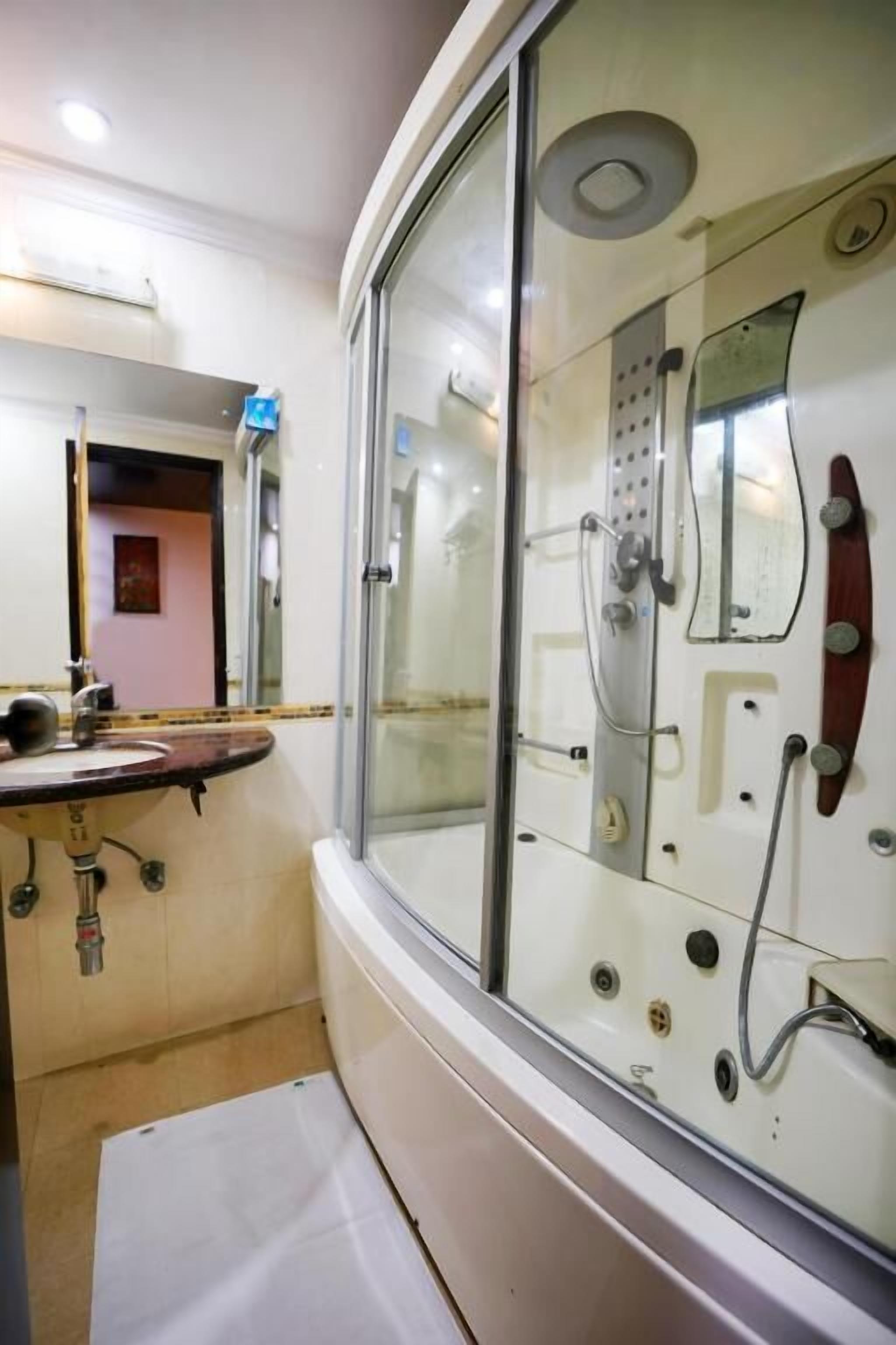A bathroom with a glass shower enclosure, a sink, and a mirror.