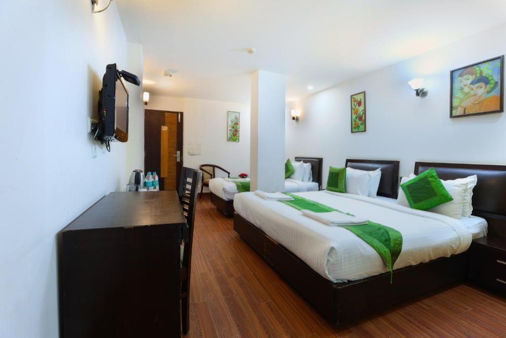 A hotel room with a large bed, a desk, and a chair. There are two bedside tables and a wall-mounted lamp.