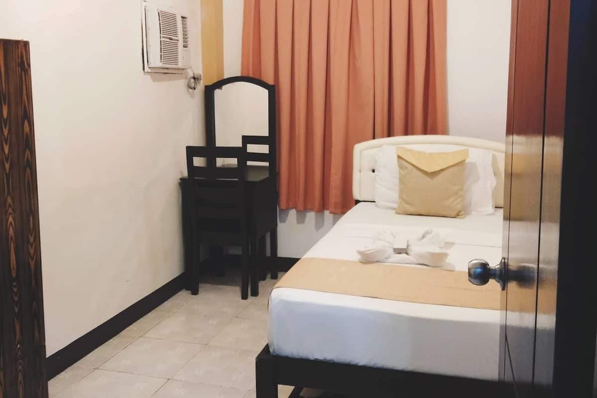 A small, clean room with a bed, a chair, and a wardrobe.
