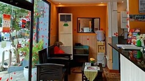 Een restaurant met een glazen wand, een eetgedeelte met tafels en stoelen, en een keuken met een aanrecht en apparatuur.