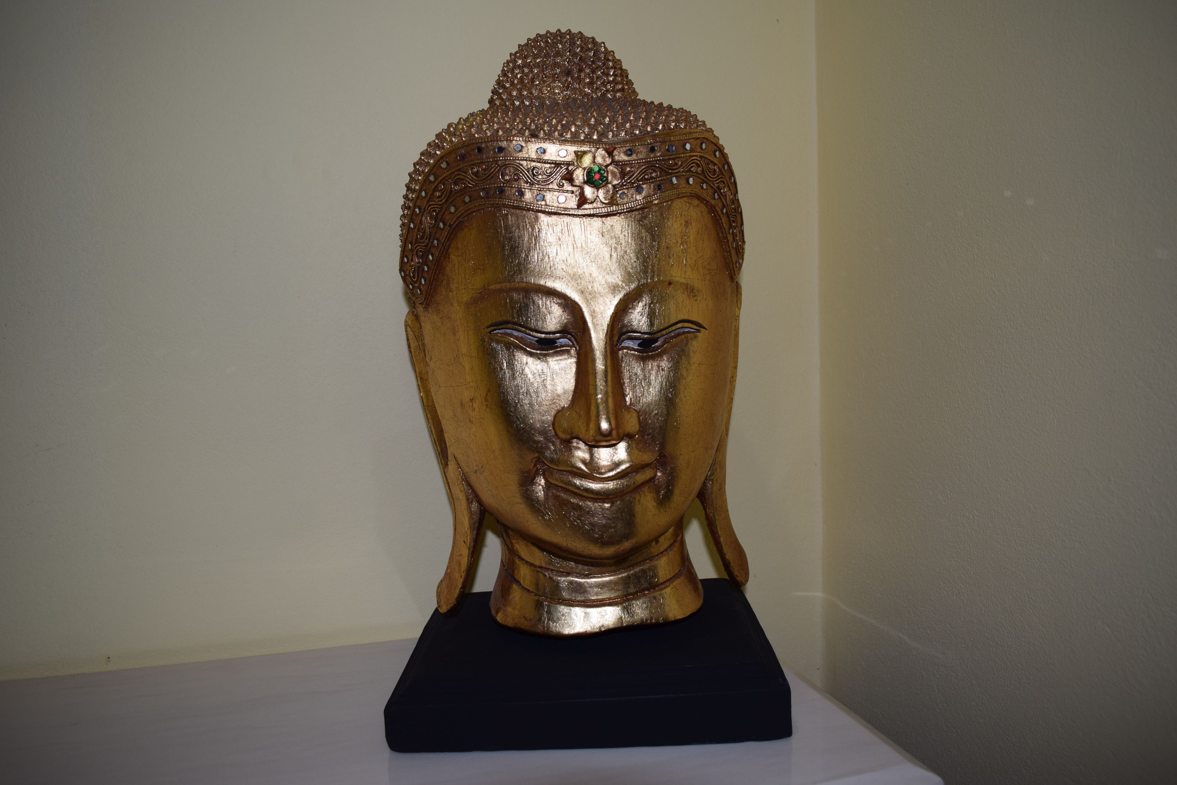 A golden Buddha statue on a black pedestal.