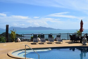 Zona de piscina con sillones y vista al mar.