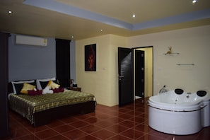A bedroom with a bed, a large window, and a bathroom with a bathtub.
