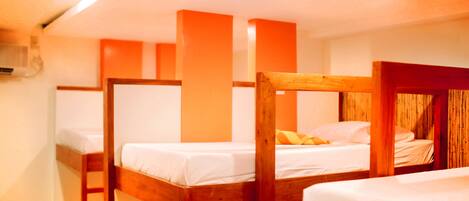 Une chambre avec des lits superposés, des têtes de lit en bois et un mur blanc.