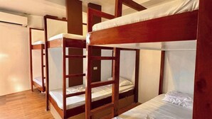 Una habitación con cuatro literas dispuestas en fila, suelo de madera e iluminación empotrada en el techo.