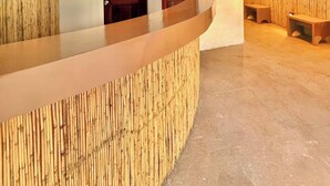 Zona de recepción con un mostrador curvo, dos puertas de madera y un área de estar con bancos.