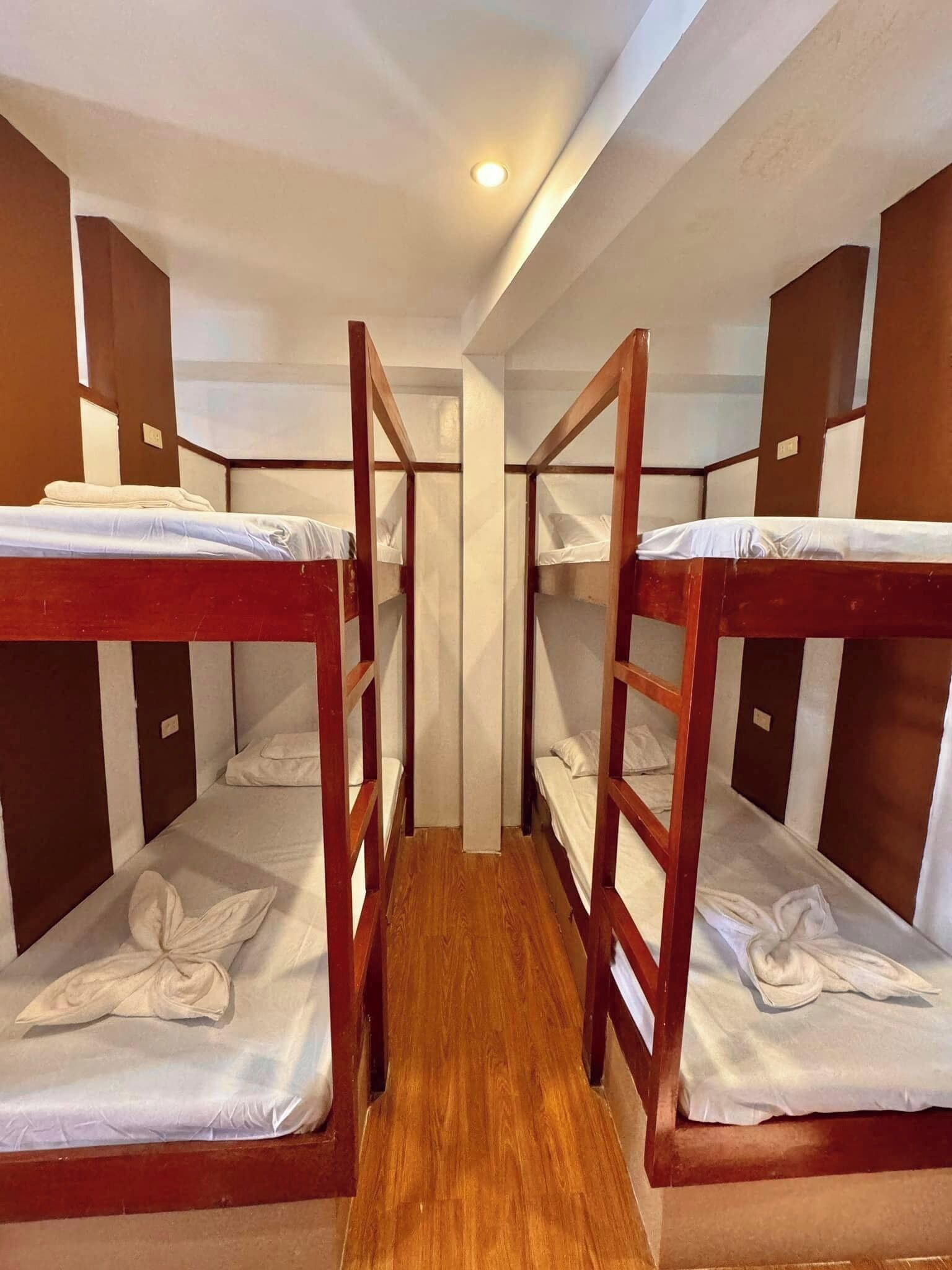 A room with bunk beds, wooden walls, and a wooden floor.