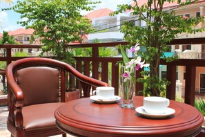 A wooden chair and table with two white cups and a vase with flowers. - 9 Dragon Hotel (Phnom Penh)
