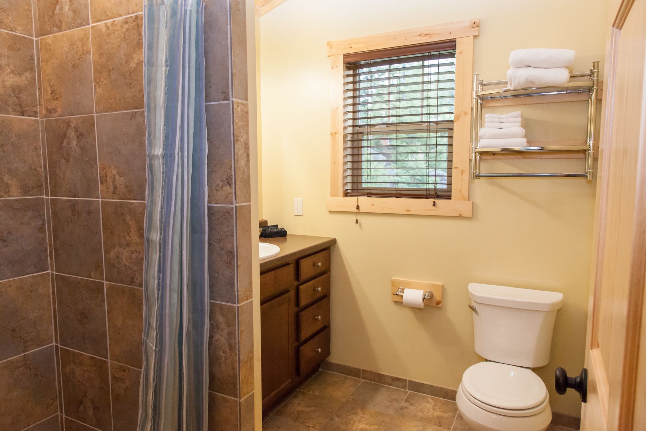 Une salle de bain équipée d’un WC, d’un lavabo, d’une fenêtre et d’un porte-serviettes.