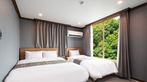 A hotel room with two beds, a large window with curtains, an air conditioning unit, and a view of greenery outside. - Port View (Yangyang)
