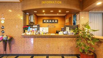 A reception area with a wooden counter, a clock, and a sign that reads "Information".
