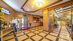 A hotel lobby with a checkered floor, a reception desk, a water dispenser, and a sign indicating a sports view. - Port View (Yangyang)
