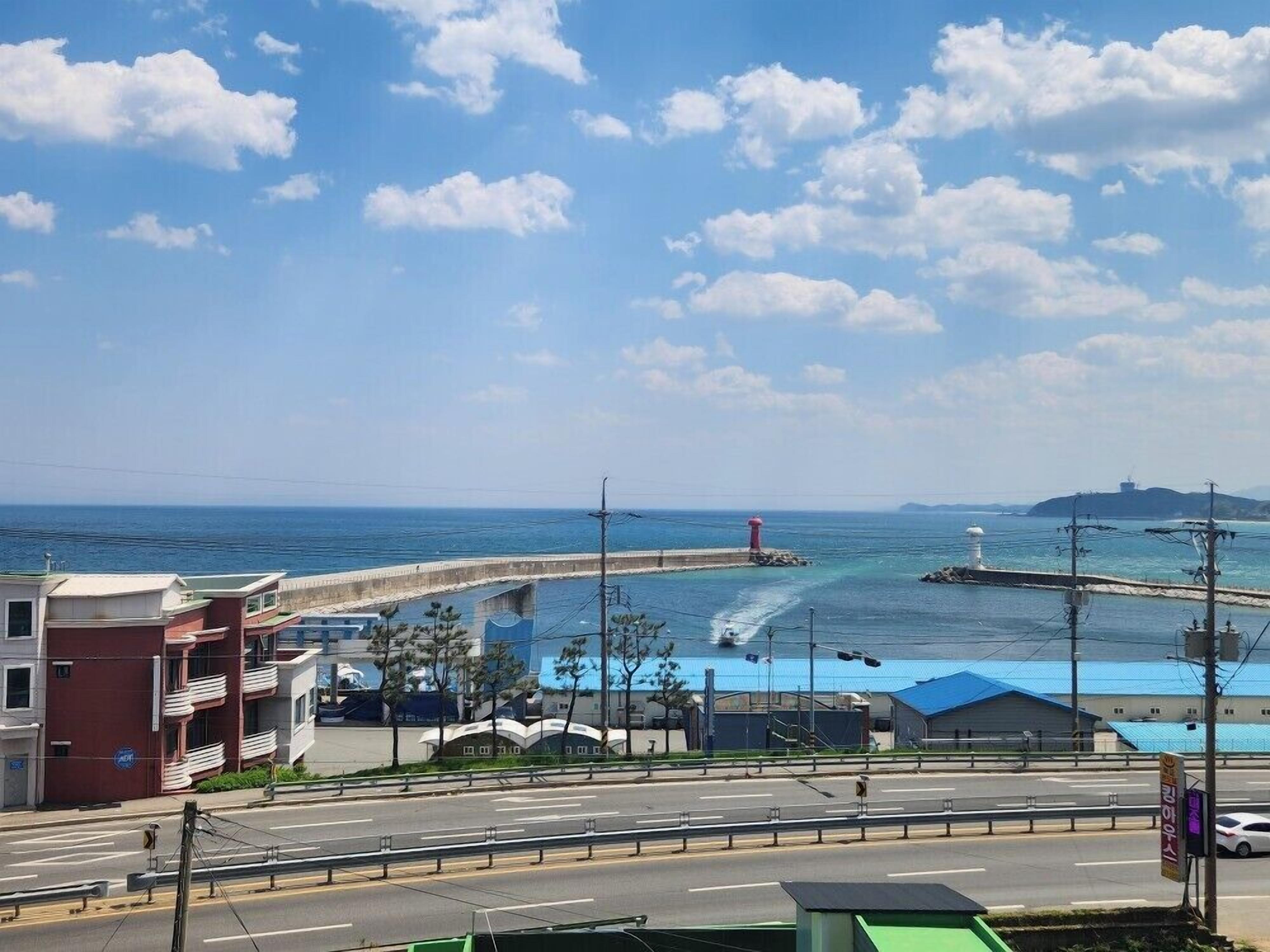 A coastal road with a sea view, a lighthouse, and a bridge.