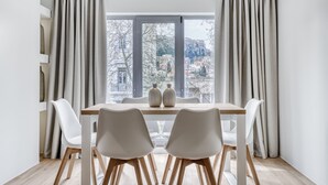 Un comedor con una mesa, sillas y vistas a un paisaje urbano a través de amplios ventanales.